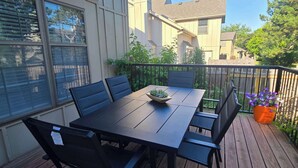 En uteplats med ett bord och stolar, en krukväxt och utsikt över de omkringliggande husen.