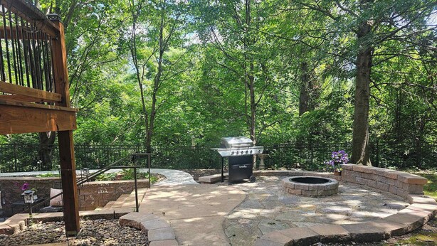 A backyard with a grill, a fire pit, and a stone pathway.