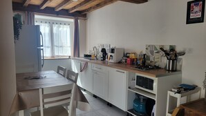A small kitchen with white cabinets, a wooden countertop, a gas stove, a microwave, and a sink.