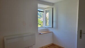 A small, narrow room with a window, a radiator, and a door.
