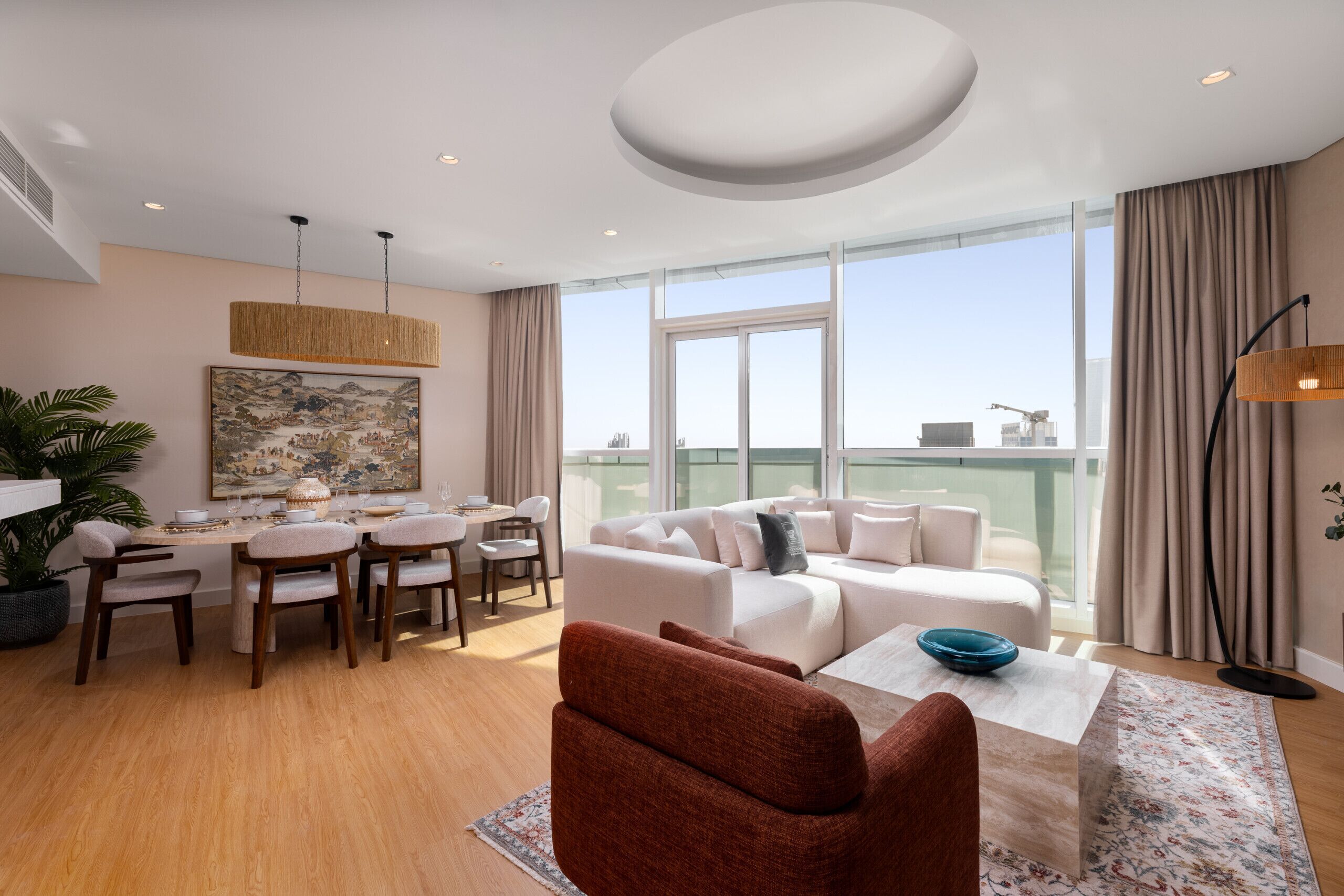 A modern living room with a sofa, dining area, and large windows offering a city view.
