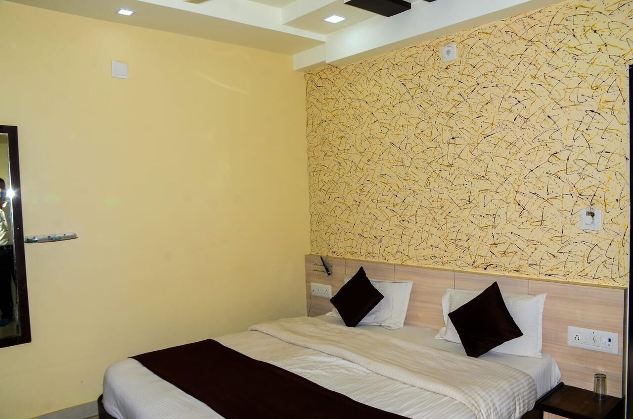 Habitación de hotel con cama, cabecero con pared texturizada y espejo en la pared.