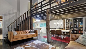 A modern living room with a leather sofa, a cowhide rug, and a dining area with a red rug. - The Roosevelt - Hot Tub, Outdoor games & Walk-to Lake (Rockbridge)
