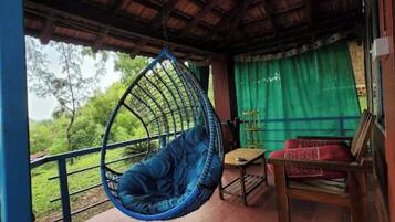 A room with a hanging chair, a small table, and a red sofa.