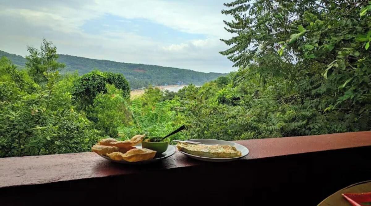 Una mesa con un plato de comida y un bol de salsa, con vistas a un paisaje verde exuberante.