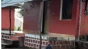 Un bâtiment de style rustique, avec une façade rouge, un toit en tuiles et un petit porche.