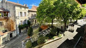 A courtyard with stone pathways, a central tree, and surrounding buildings with balconies and windows. - Le Logis Plantagenêt (Bergerac)