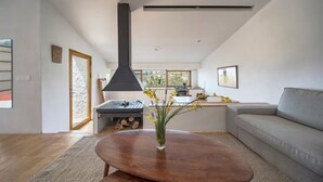 A modern living room with a large black chimney, a grey sofa, and a wooden coffee table with a vase of flowers. - El Castillete – Charm with Sea Views (La Garnatilla)