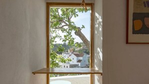 A room with a view of a tree and buildings through a window. - El Castillete – Charm with Sea Views (La Garnatilla)