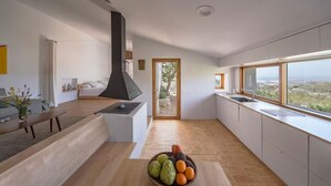 A modern kitchen with a large window, a wooden bench, and a bowl of fruit on the counter. - El Castillete – Charm with Sea Views (La Garnatilla)