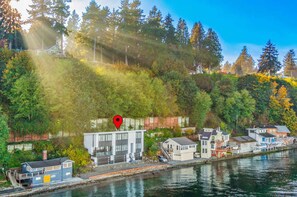 A waterfront property with a modern building, a dock, and a forested hillside.