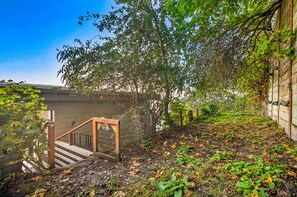 A staircase leading to a building with a covered outdoor area, surrounded by greenery and a clear sky.