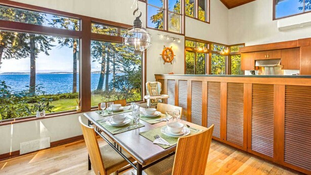 A modern kitchen with large windows overlooking a scenic view. - Poulsbo's Waterfront Lodge · Puzzle Point (Poulsbo)