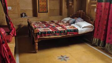Una habitación con una cama de madera, aire acondicionado en la pared y un tapete estampado.