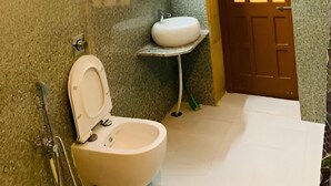 A bathroom with a toilet, sink, and a door with a window. - Hotel Choti Haveli (Jaisalmer)