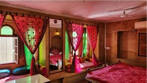 A traditional room with a bed, a window with curtains, and a wooden ceiling. - Hotel Choti Haveli (Jaisalmer)