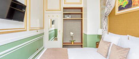 A hotel room with a bed, a television, a wardrobe, and a painting on the wall.