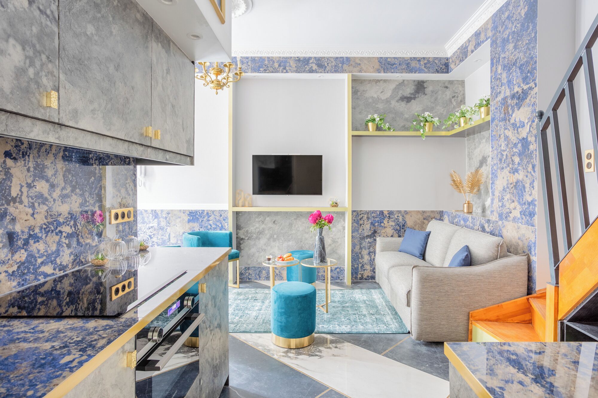 A modern living room with a marble floor, a blue sofa, a coffee table, and a TV mounted on the wall.