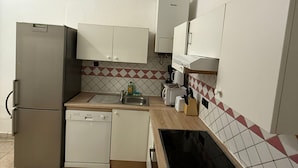 Una cocina compacta equipada con refrigerador, lavavajillas y microondas.