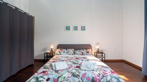 A bedroom with a floral bedspread, two bedside tables with lamps, a headboard, and three framed pictures on the wall. - Vanna's House near the center of Florence (Firenze)