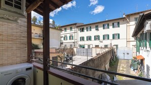 A balcony with a washing machine, a view of a narrow street with buildings, and a clear blue sky. - Vanna's House near the center of Florence (Firenze)