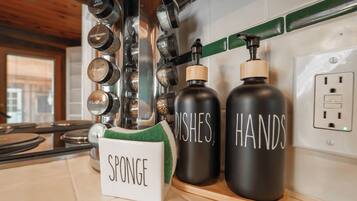 A kitchen with a spice rack, a sponge holder, and two containers labeled "DISHES" and "HANDS".