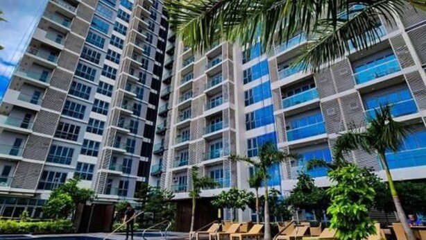 Um edifício residencial alto com piscina e palmeiras.