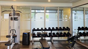 Uma academia com equipamentos de ginástica, um banco e uma estante de halteres.