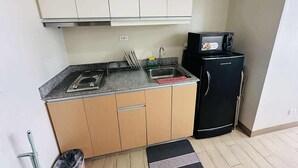 Uma cozinha compacta com fogão, pia e geladeira preta.