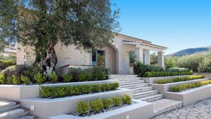 A stone building with a terraced garden, steps leading to the entrance, and a tree in the foreground. - Thea Estate (Corfu)