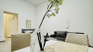 Ein modernes Wohnzimmer mit Esstisch, Stühlen, einer Couch und einer Zierpflanze.