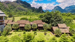 Un complexe hôtelier composé de plusieurs bâtiments de style bungalow, entouré d’une végétation luxuriante et de montagnes.