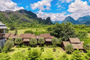 Un resort con varias edificaciones tipo bungaló, rodeado de exuberante vegetación y montañas.