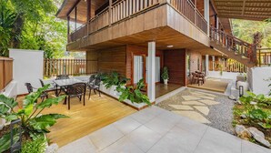 Une maison en bois dotée d’un balcon, d’un espace salon extérieur et d’un escalier.