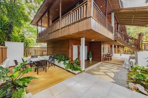 Una casa de madera con balcón, mobiliario exterior y una escalera.