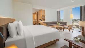 Habitación de hotel con cama, sofá, mesa de centro y vistas de la ciudad.