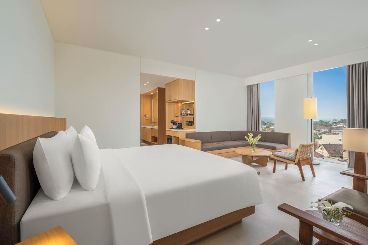Habitación de hotel con cama, sofá, mesa de centro y vistas de la ciudad.