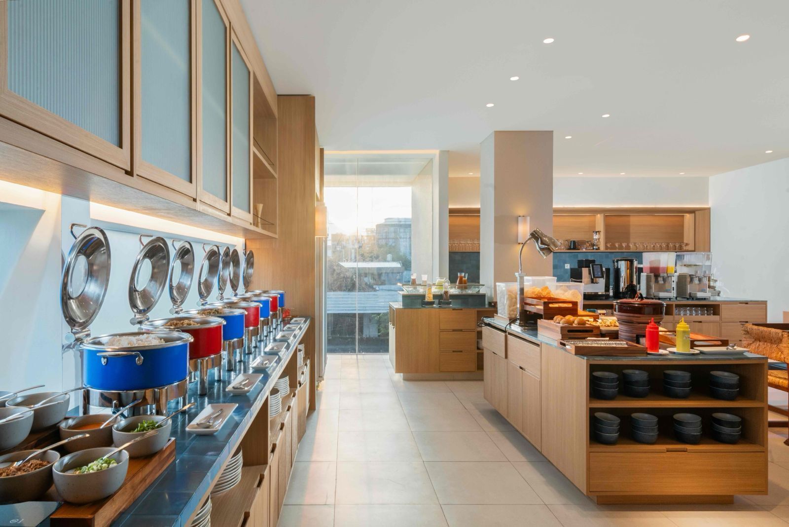 A modern kitchen with a buffet setup, wooden cabinets, and a view to the outside.
