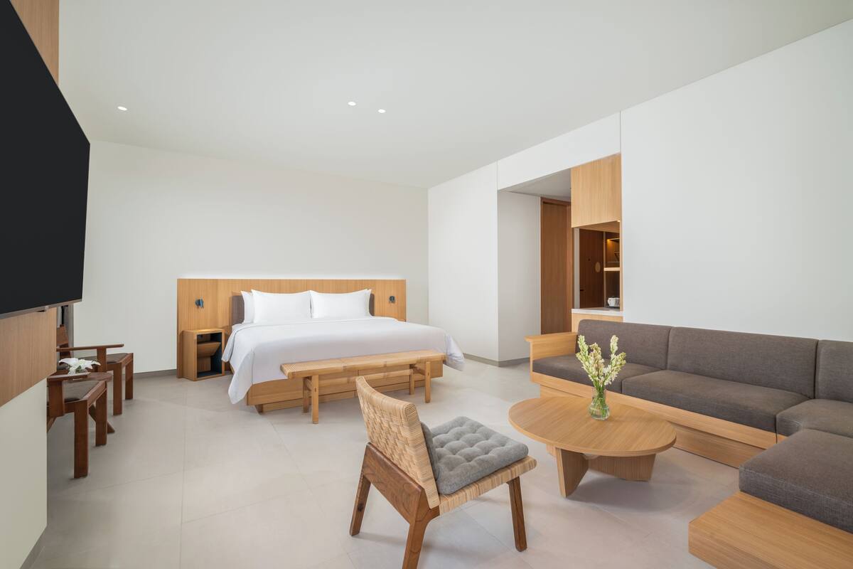 Una habitación de hotel moderna con cama, sofá, mesa de centro y televisor.