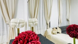 Een slaapkamer met een bed, gordijnen en een lamp.