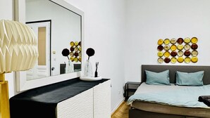 Een slaapkamer met een bed, nachtkastjes, een spiegel en een kunstwerk aan de muur.