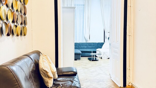 Een woonkamer met een leren bank, een salontafel en een decoratief object aan de muur.