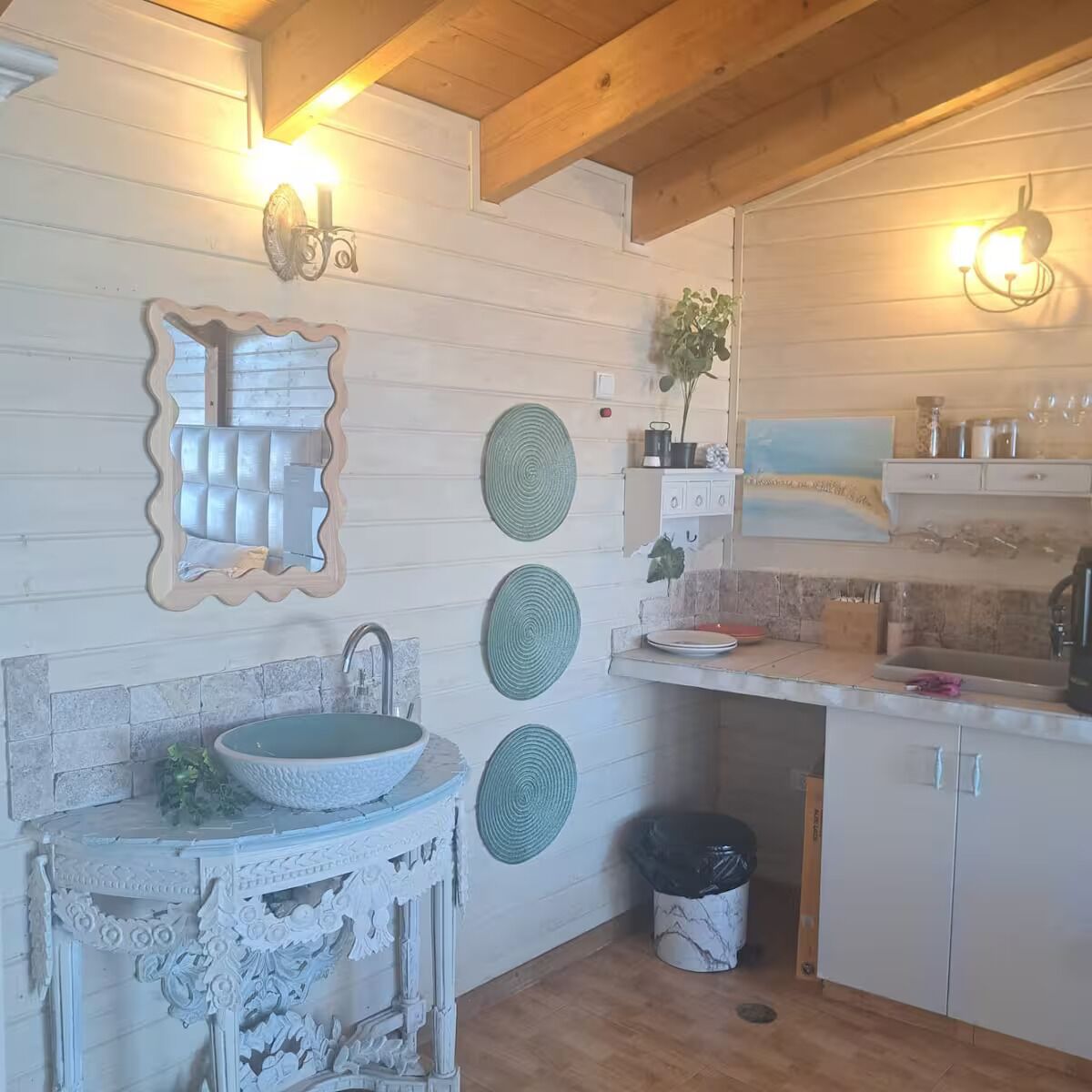 Een keuken met een houten plafond, een decoratieve spiegel, een spoelbak en een prullenbak.