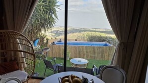 Une pièce avec vue sur un jardin, une piscine et un coin repas comprenant une table et des chaises.