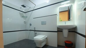 A small, compact bathroom with a toilet, a sink, and a shower. - Hotel Mountain Hues Thekkady (Udumbanchola)
