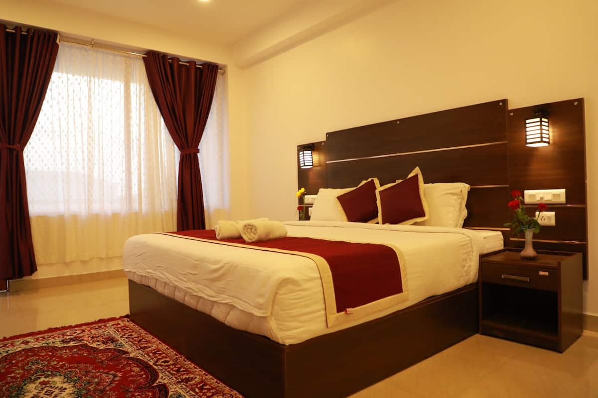 Une chambre d’hôtel moderne avec un grand lit, une tête de lit en bois foncé et une couvre-lit rouge et blanche.