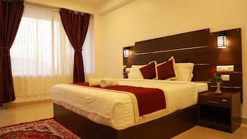 Una habitación de hotel moderna con una cama grande, cabecera de madera oscura y una colcha roja y blanca.