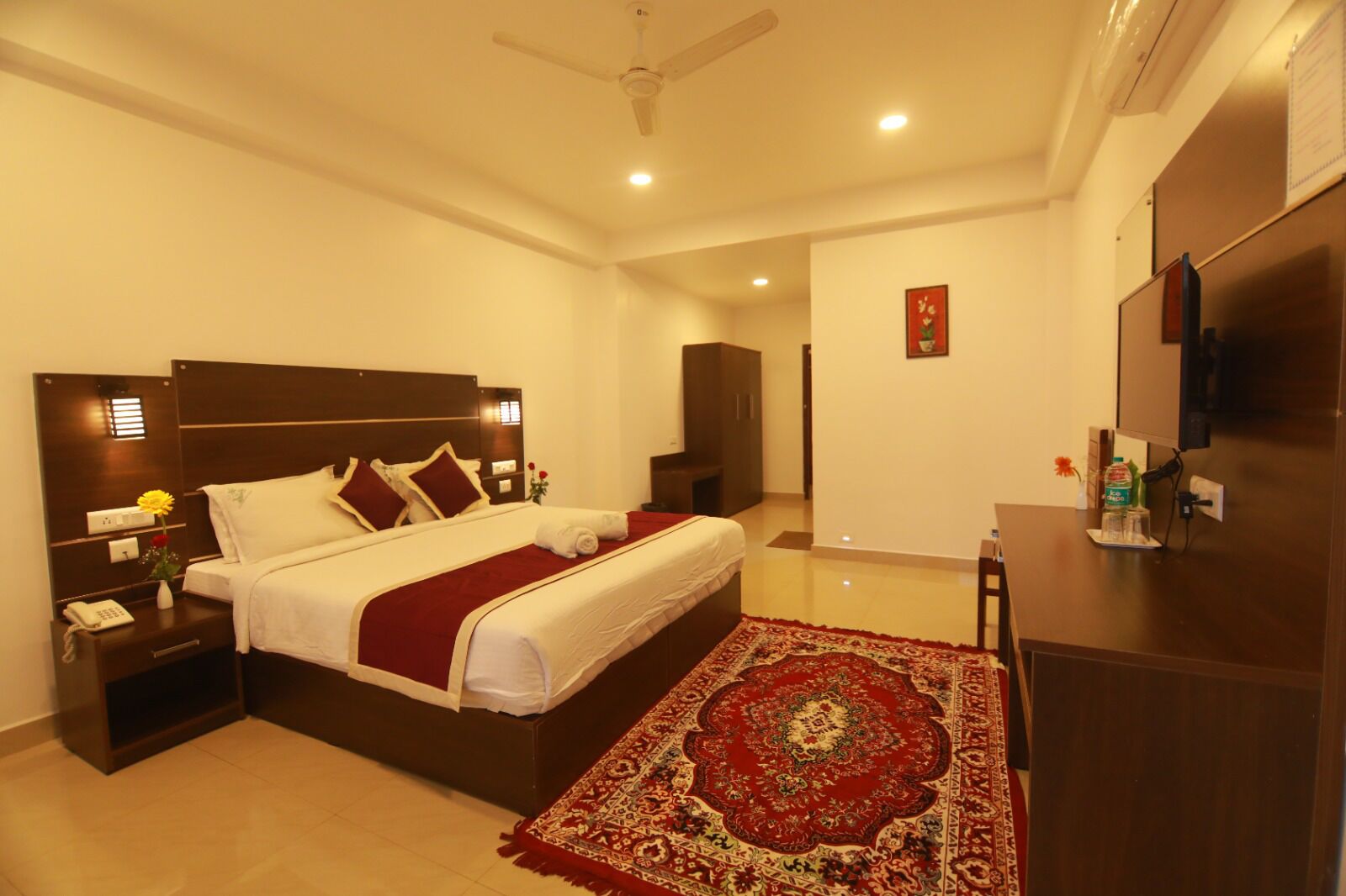 A hotel room with a large bed, a desk, a television, and a wardrobe.