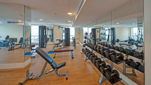 A gym with various exercise equipment, including dumbbells and benches, and large mirrors on the walls. - Belvilla Marina View Suites, Dubai Marina (Dubai)
