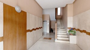 A hallway with a wooden door, a staircase, and a potted plant.
